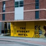 Modern brick building with vibrant graffiti art and street view in city setting.