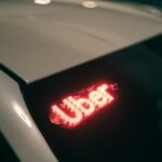 Close-up of a ride-sharing car with a bright red illuminated sign for night-time travel.