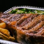 Close-up of a juicy grilled steak with fries and greens. Perfect meal for steak lovers.