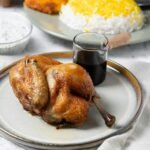 Perfectly roasted chicken served with Persian rice, saffron, and a side of sauce.