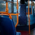A quiet interior of a public bus with vibrant blue and orange seating, United Kingdom.