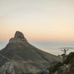 Silhouette of a hiker celebrating at sunset near Lion's Head in Cape Town.