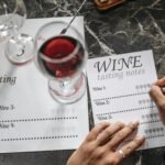Close-up of wine tasting session with notes, glasses, and marble surface.